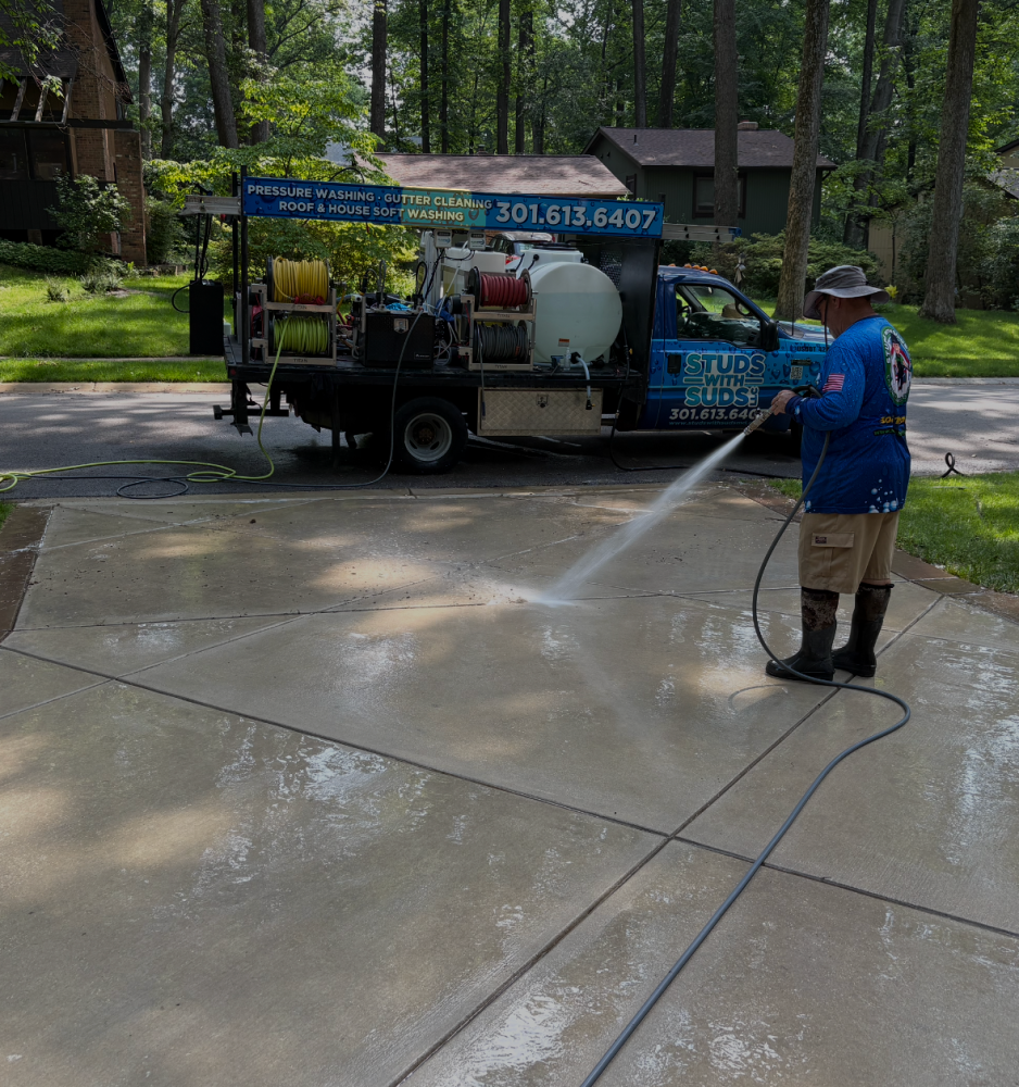 1-columbia-pressure-washing-truck-action Studs With Suds crew member pressure washing a concrete driveway in Columbia, Maryland, with the truck behind him