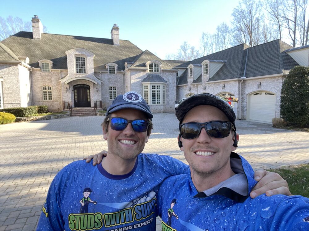 Two Studs With Suds crew members wearing branded shirts at a house-washing job